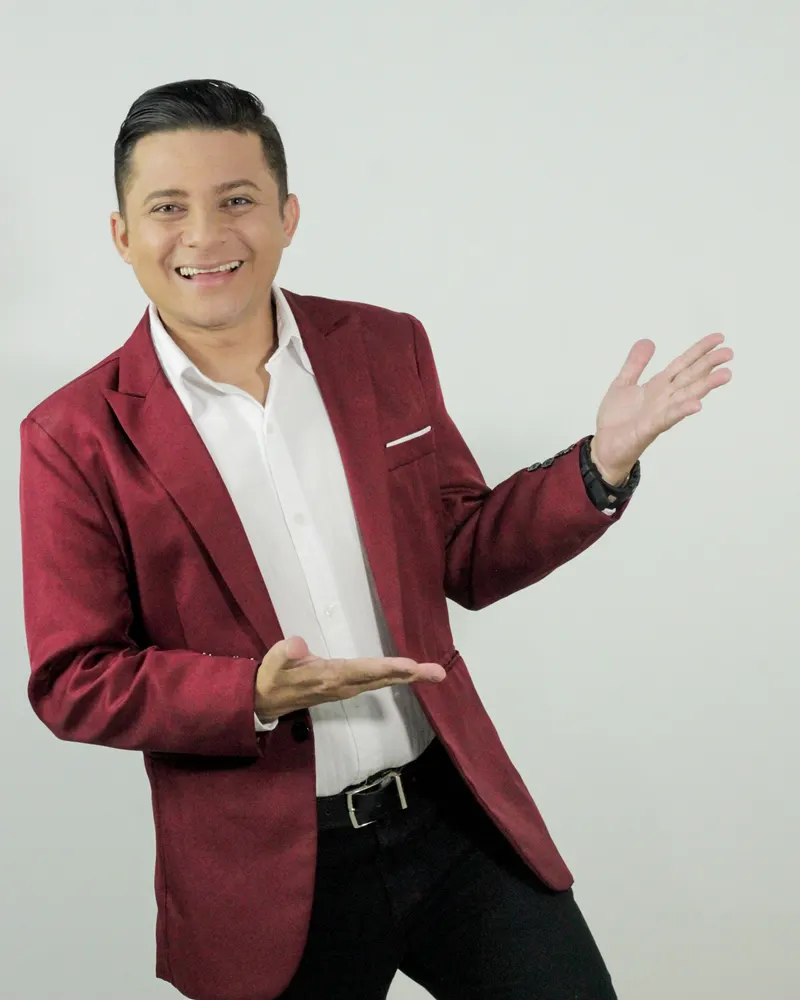 Leo da TV de blazer vinho, sorrindo, com as mãos apontando para o lado